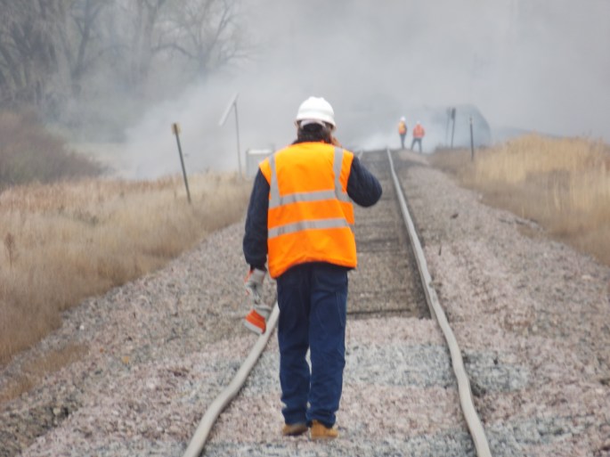 A BNSF maintenance worker stops to talk on his cell phone while inspecting the tracks just east of the accident site. Just ahead of him is the end of the stretch where the track has beeen raised 
